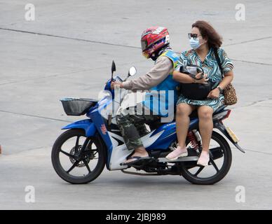 SAMUT PRAKAN, THAILAND, APR 02 2022, Ein Taxifahrer auf einem Motorrad fährt mit einer Frau. Das Moto-Taxi trägt einen Passagier Stockfoto