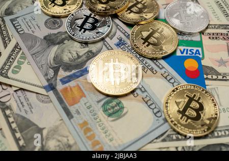 Manhattan, New York/USA - März 26. 2021: Bitcoin auf Dollar-Banknoten und Visa-Kreditkarte neben Mastercard-Debitkarte. Krypto-Währung mit Plastik Stockfoto