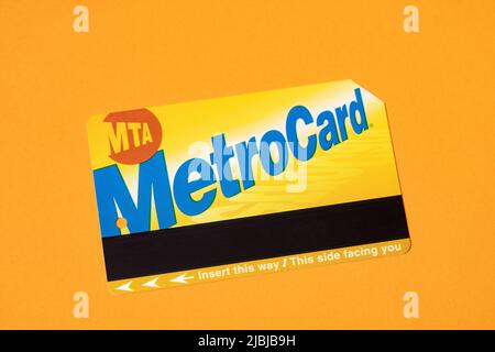 Manhattan, New York/USA - April 8. 2021: New York City Metrocard auf orangefarbenem Hintergrund. Ticket für den öffentlichen Nahverkehr in NYC Stockfoto