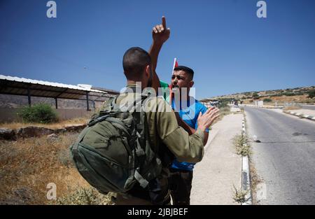 27. Mai 2022, Jordantal, Westbank, Palästina: Ein israelischer Soldat unterdrückt einen palästinensischen Demonstranten, der eine palästinensische Flagge trägt, während der Demonstration gegen die Landkonfiszierung im nördlichen Jordantal im besetzten Westjordanland. (Bild: © Nasser Ishtayeh/SOPA Images via ZUMA Press Wire) Stockfoto