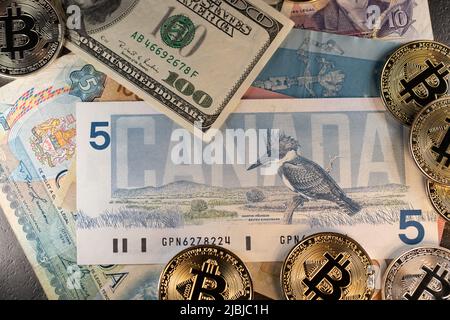 Toronto, Kanada - Oktober 30. 2021: Bitcoin-Handel mit kanadischen und US-Dollar. Kryptowährung auf 5 kanadischen und 100 US-Dollar-Banknoten Stockfoto