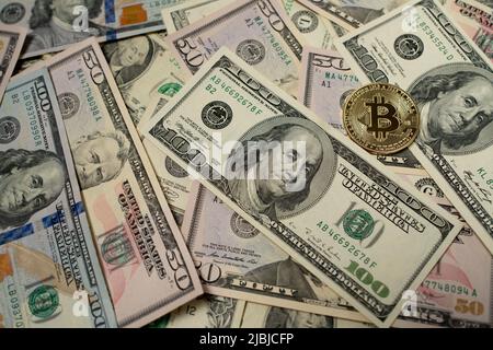 Bitcoin auf Dollar-Banknoten. Ein 100-Dollar-Schein neben einer Bitcoin-Goldmünze. Krypto-Austauschkonzept Stockfoto