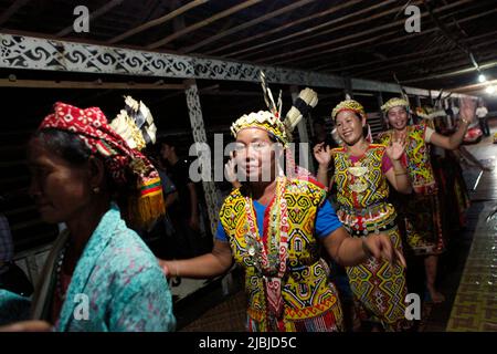 Frauen, die in einer Schlange tanzen, begrüßen Gäste während einer Ökotourismus-Veranstaltung im Bali Gundi Longhouse der traditionellen Dayak Taman-Gemeinde in Sibau Hulu, Putussibau Utara, Kapuas Hulu, West Kalimantan, Indonesien. Stockfoto