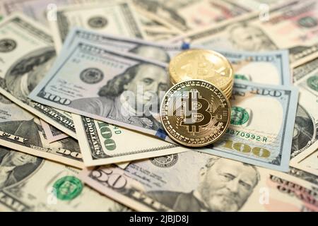 Bitcoin-Münze auf 100-Dollar-Banknoten aus den vereinigten Staaten von amerika. Digitale Krypto-Währung und US-Dollar-Währung. Gold glänzende Münzen auf Haufen Stockfoto