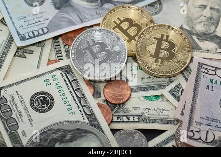 Bitcoin-Münzen auf Dollar-Banknoten, fünfzig und hundert Dollar-Scheine. US-Währung und BTC-Kryptowährung Stockfoto