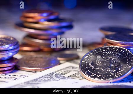 Auf den Banknoten stapelten sich Dollarmünzen. Geld und Bargeld aus den USA. Markt- und Handelskonzept. Eine halbe Dollar-Münze reflektiert Licht Stockfoto