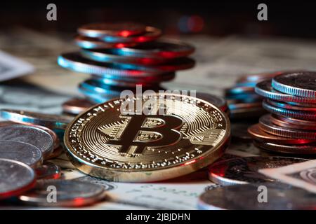 Goldbitcoin neben Dollarmünzen und Banknoten. US-Dollar-Bargeld stapelte Münzen und Papiergeld als Hintergrund auf. Krypto-Währung und Blockchain-Technologie Stockfoto