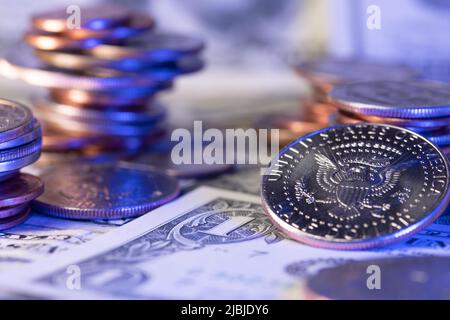 Eine halbe Dollar-Münze mit Adler, daneben stapelten wir Dollar-Münzen. Dollar-Banknoten als Hintergrund. Wirtschaft und Wohlstand in den Vereinigten Staaten von Amerika Stockfoto