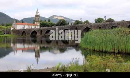 Mittelalterliche Steinbrücke über den Fluss Lima, Kirche Santo Antonio da Torre Velha aus dem 18.. Jahrhundert auf der gegenüberliegenden Flussseite, Ponte de Lima, Portugal Stockfoto