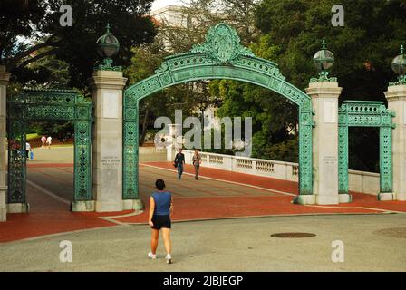 Ein Student spaziert durch die historischen Tore von Sather und den Eingang zum Campus der University of California in Berkeley Stockfoto