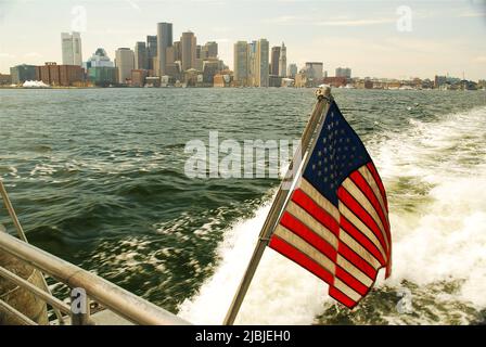 Eine amerikanische Flagge winkt auf der Rückseite einer Fähre, wenn sie den Pier in Boston verlässt Stockfoto