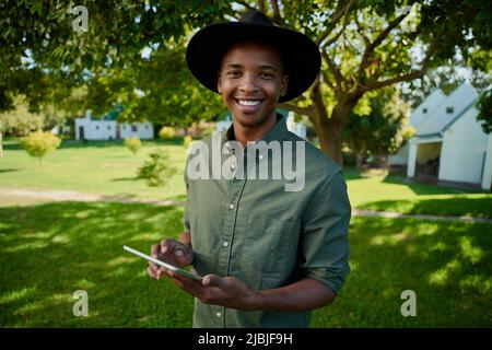Gemischter Rassenbauer, der auf einem digitalen Tablet im Freien steht, tippt Stockfoto