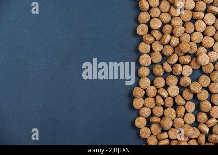 Trockene Futterpellets vor grauem Hintergrund. Braune runde Pellets. Gesundes Futter für Haustiere. Platz für Text- und Designelemente kopieren. Abgewinkelte Ansicht von Stockfoto