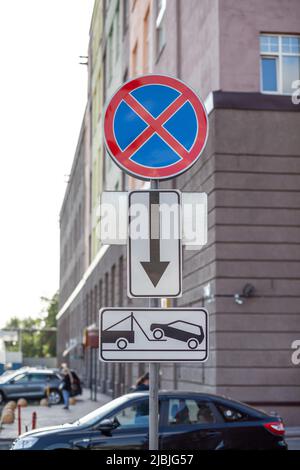 Das Straßenschild verbietet das Anhalten vor dem Hintergrund von Gebäuden und Autos. Nahverkehrsschilder Keine Haltestellen und Abschleppzone in der Stadt. Straßenschilder o Stockfoto