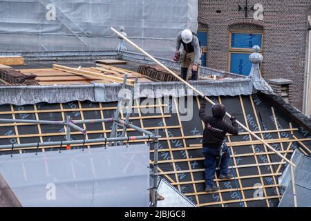 Amsterdam, Niederlande 24. Mai 2022. Dämmarbeiten an der Dachkonstruktion des Gebäudes. Teamarbeit, Arbeiter mit Schutzausrüstung auf dem Dach, Metallgerüst Stockfoto