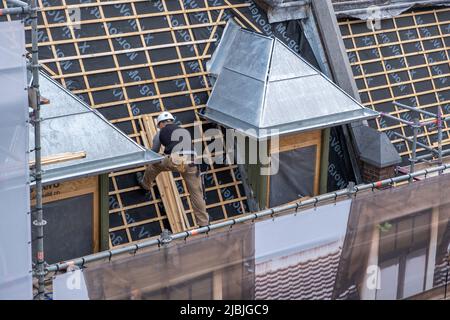 Amsterdam, Niederlande 24. Mai 2022. Dämmarbeiten an der Dachkonstruktion des Gebäudes. Arbeiter mit Schutzausrüstung auf dem Dach, Metallgerüst Stockfoto