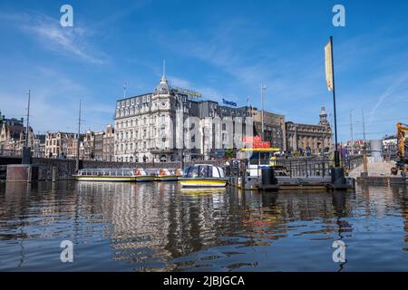 Amsterdam, Niederlande 22. Mai 2022. Hafen mit festfahrtem Kanalkreuzfahrtschiff für Besichtigungstouren in Holland. Traditionelles Architekturgebäude, Reflexion über W Stockfoto