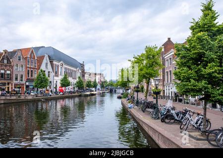 Leiden, Niederlande 23. Mai 2022. Traditionelles Architekturgebäude, Café am Wasser im Freien, Boot im Kanalwasser festgemacht, Fahrrad geparkt Stockfoto