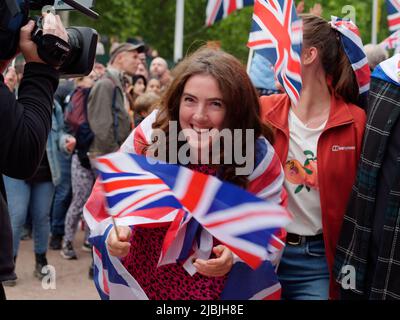 London, Greater London, England, 04 2022. Juni: Jubilee Concert at the Mall. Eine Frau, die mit einer Union Jack-Flagge drapiert ist, lächelt. Stockfoto