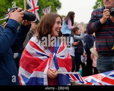 London, Greater London, England, 04 2022. Juni: Jubilee Concert at the Mall. Eine Frau, die mit einer Union Jack-Flagge drapiert ist, lächelt. Stockfoto