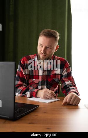 Erwachsene Studenten schreiben Informationen von einem Laptop auf, während sie sich auf einen Vortrag auf einem Universitätscampus vorbereiten, während ein Hipster auf einem PC arbeitet Stockfoto
