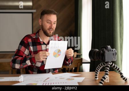 Männlich im Hemd zeigen Statistik-Grafik-Pad machen Promo-Videoblog oder Foto-Session in Camcorder zu Stativ. Vlogger Selfie-Verkaufslösung oder Finanzberater Stockfoto