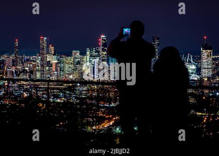 Brisbane, Australien - Silhouetten von Menschen, die Fotos von der Nachtstadt am Mount Coot-Tha Summit Lookout machen Stockfoto