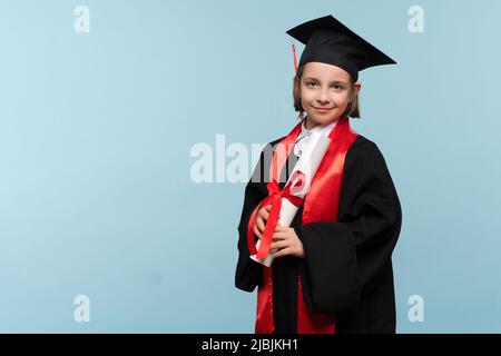 Whizz Kind 9-11 Jahre Mädchen trägt Abschlusskappe und Zeremonie Robe mit Zertifikat Diplom auf hellblauem Hintergrund. Absolvent feiert seinen Abschluss. Stockfoto