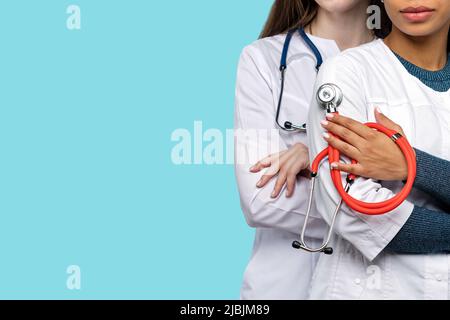Team von nicht erkennbaren Ärztinnen Nahaufnahme mit medizinischen Stethoskop auf blauem Hintergrund im Studio. Stockfoto