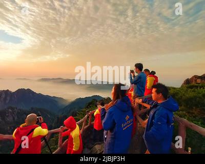 (220607) -- HUANGSHAN, 7. Juni 2022 (Xinhua) -- Touristen sehen den Sonnenaufgang auf dem Berg Huangshan, 5. Juni 2022. Der Berg Huangshan, der auch als Gelber Berg bekannt ist, liegt in der ostchinesischen Provinz Anhui und ist bekannt für seine herrliche Naturlandschaft mit massiven Granitfelsen und uralten Kiefern, die oft durch Wolken- und Nebeleffekte verstärkt werden. Das Anwesen verfügt über zahlreiche imposante Gipfel, von denen viele eine Höhe von 1.000 Metern überschreiten, wobei der höchste, der berühmte Lianhua Peak (Lotus Peak), bis zu 1.864 Meter erreicht. Huangshan ist auch berühmt für seine alten Wege, Stockfoto