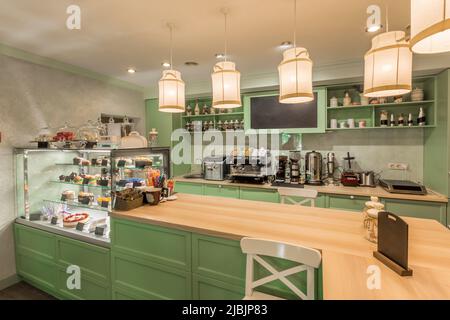 Gemütliches Café mit pastellgrüner Theke und Glasvitreen mit Desserts Stockfoto