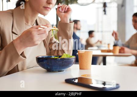 Nahaufnahme einer jungen Frau, die am Tisch im Café eines Einkaufszentrums asiatischen Essensalat isst, Kopierbereich Stockfoto