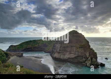 Taitomo Rock direkt am Piha Beach, Neuseeland, an einem stürmischen Tag Stockfoto