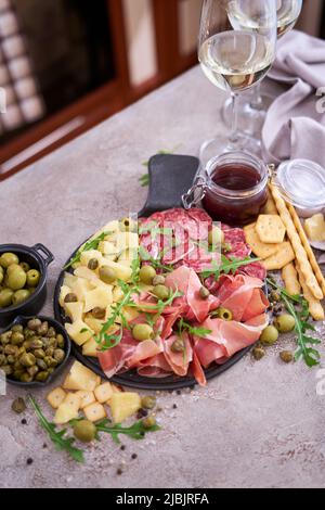 Zwei Gläser Weißwein und italienische Antipasto-Fleischplatte in der heimischen Küche Stockfoto