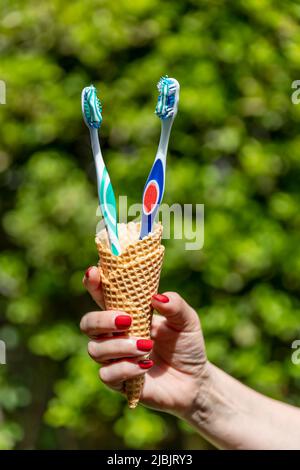 Zwei Zahnbürsten mit Zahnpasta werden in einen Kegel gelegt, wie die für Eiscreme Stockfoto