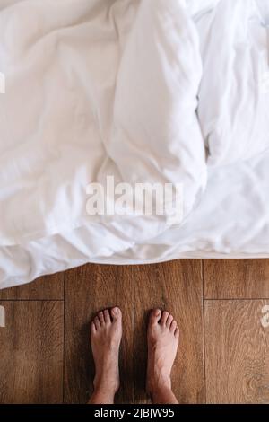 Barfuß-Mann, der vor dem Bett steht, Draufsicht Stockfoto