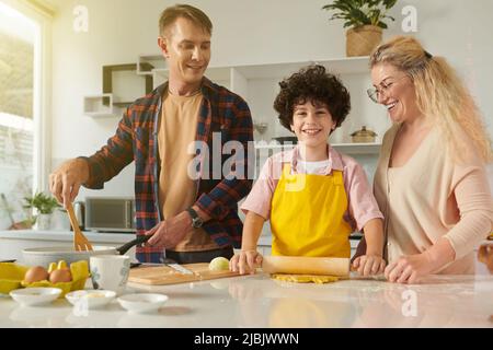 Glückliche Familie von drei Kochen Pasta und Sauce zum Abendessen zusammen Stockfoto