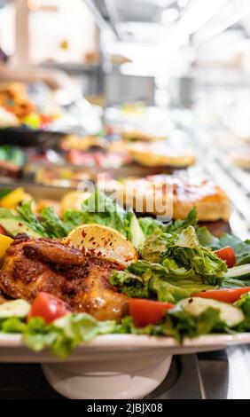 Tabakhuhn mit Zitrone und Tomate unter anderem außer Fokus geratenes Abendessen. Selektiver Fokus, vertikaler Kopierbereich Stockfoto