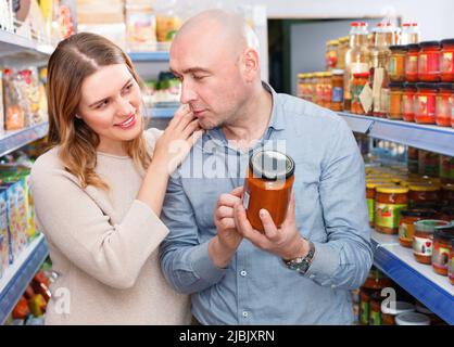 Positives Familienpaar, das Konserven im Lebensmittelgeschäft hält Stockfoto