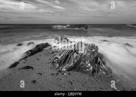 Langzeitaufnahme von Wellen, die über Felsen an der nordkornischen Küste brechen Stockfoto