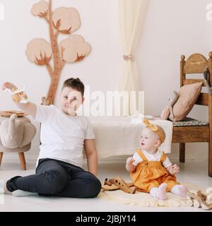 Niedliche Kinder, Geschwister spielen zu Hause, älterer Bruder und kleine Schwester im Kinderzimmer zu Hause Stockfoto