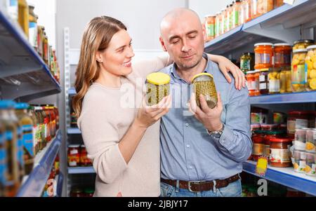 Positives Familienpaar, das Konserven im Lebensmittelgeschäft hält Stockfoto