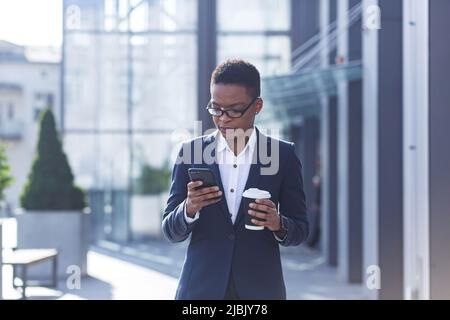 Geschäftsfrau mit Mobiltelefon, seriöse afroamerikanische Mitarbeiterin außerhalb des Büros Stockfoto