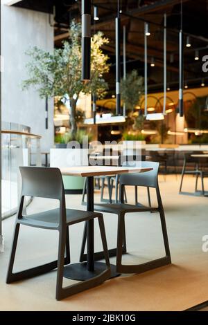 Vertikales Hintergrundbild von Tisch und Stühlen im Loft-Stil Food Court Interieur Stockfoto