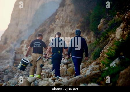 7. Juni 2022, Montecito, CA, USA: Feuerwehrleute der Feuerwehr Montecito haben am 6. Juni 2022 am Butterfly Beach, einem typisch unberührten Küstenstreifen in einer der exklusivsten und reichsten Städte der USA, ein wüstendes Lagerfeuer ausgelöst, das von einem wohlmeinenden, aber fehlgeleiteten Bewohner von Goleta, Kalifornien, namens Joey, begonnen wurde. Die, verärgert über die Trümmer, die vom verlassenen und illegalen Obdachlosenlager am Butterfly Beach hinterlassen wurden, das Feuer anzündete, um den Müll zu verbrennen. Dies dauerte weniger als 24 Stunden, nachdem die Feuerwehrleute gekämpft und das nahegelegene Brückenfeuer eingedämmt hatten, sodass Bewohner und Ersthelfer besonders nervös waren und vi Stockfoto