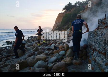 7. Juni 2022, Montecito, CA, USA: Feuerwehrleute der Feuerwehr Montecito haben am 6. Juni 2022 am Butterfly Beach, einem typisch unberührten Küstenstreifen in einer der exklusivsten und reichsten Städte der USA, ein wüstendes Lagerfeuer ausgelöst, das von einem wohlmeinenden, aber fehlgeleiteten Bewohner von Goleta, Kalifornien, namens Joey, begonnen wurde. Die, verärgert über die Trümmer, die vom verlassenen und illegalen Obdachlosenlager am Butterfly Beach hinterlassen wurden, das Feuer anzündete, um den Müll zu verbrennen. Dies dauerte weniger als 24 Stunden, nachdem die Feuerwehrleute gekämpft und das nahegelegene Brückenfeuer eingedämmt hatten, sodass Bewohner und Ersthelfer besonders nervös waren und vi Stockfoto