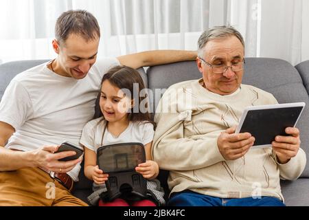 Großvater und Enkelin, Vater mit Smartphone zu Hause Stockfoto