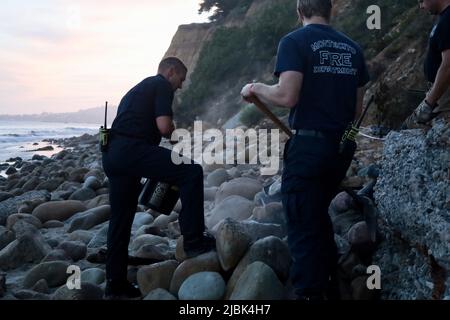 7. Juni 2022, Montecito, CA, USA: Feuerwehrleute der Feuerwehr Montecito haben am 6. Juni 2022 am Butterfly Beach, einem typisch unberührten Küstenstreifen in einer der exklusivsten und reichsten Städte der USA, ein wüstendes Lagerfeuer ausgelöst, das von einem wohlmeinenden, aber fehlgeleiteten Bewohner von Goleta, Kalifornien, namens Joey, begonnen wurde. Die, verärgert über die Trümmer, die vom verlassenen und illegalen Obdachlosenlager am Butterfly Beach hinterlassen wurden, das Feuer anzündete, um den Müll zu verbrennen. Dies dauerte weniger als 24 Stunden, nachdem die Feuerwehrleute gekämpft und das nahegelegene Brückenfeuer eingedämmt hatten, sodass Bewohner und Ersthelfer besonders nervös waren und vi Stockfoto