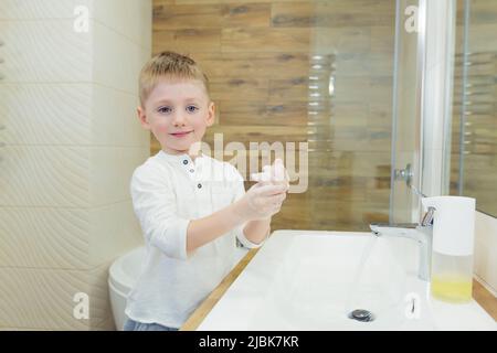 Der kleine Junge wäscht sich die Hände mit Seife, desinfiziert im Badezimmer, zu Hause, im Restaurant, im Hotel, im Einkaufszentrum Stockfoto