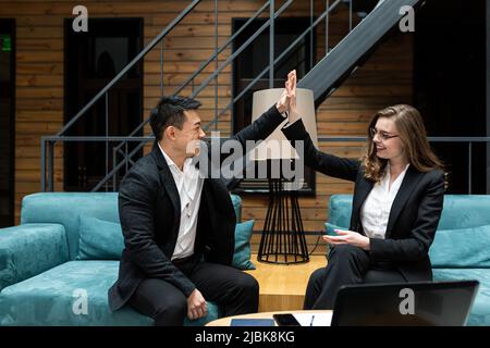 Lächelnde Kollegen feiern den Unternehmenssieg, das Erreichen des Ziels am Arbeitsplatz, fünf erfolgreiche Geschäftspartner im Team Stockfoto